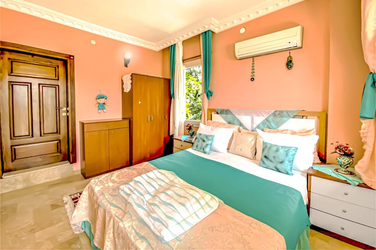 A bedroom with a bed, a wardrobe, a nightstand, and a window with curtains.