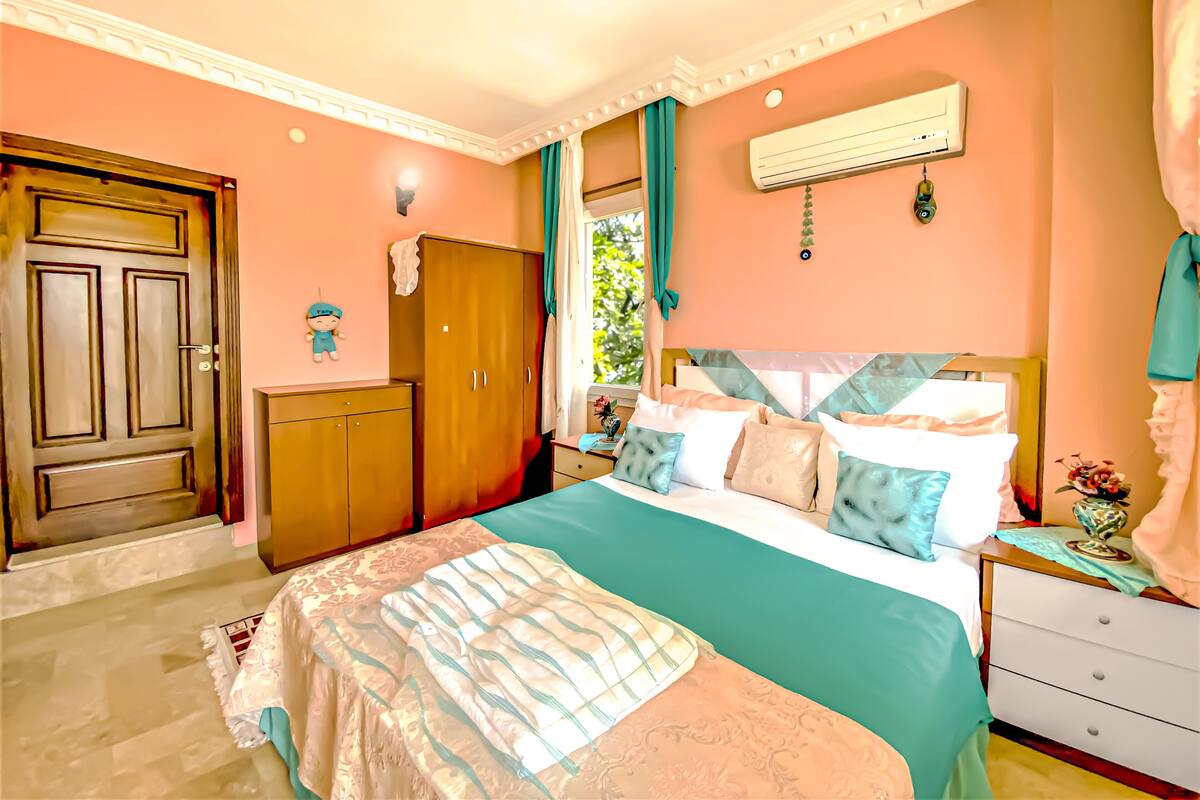 A bedroom with a bed, a wardrobe, a nightstand, and a window with curtains.