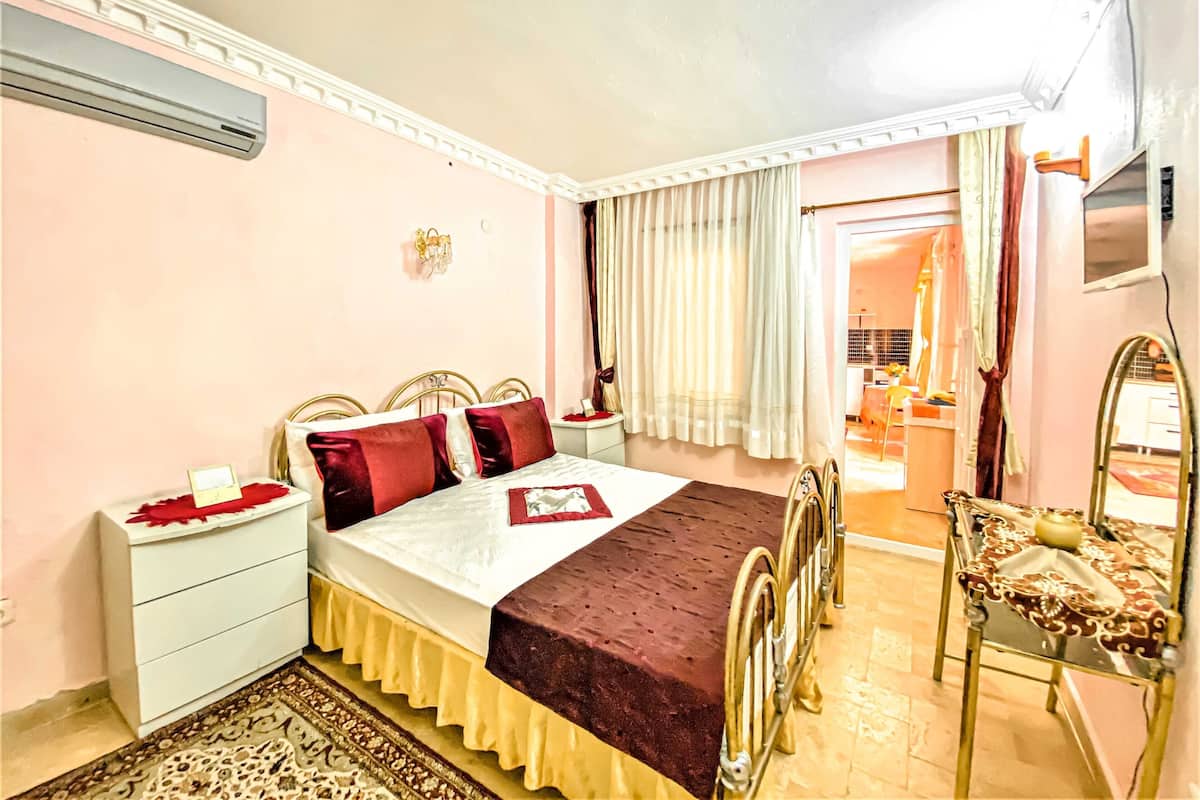 A hotel room with a bed, bedside tables, a desk, and a chair.