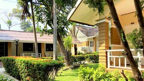 A hotel with a covered outdoor seating area, neatly trimmed hedges, and a well-maintained lawn. - Malibu Samed resort (Rayong)