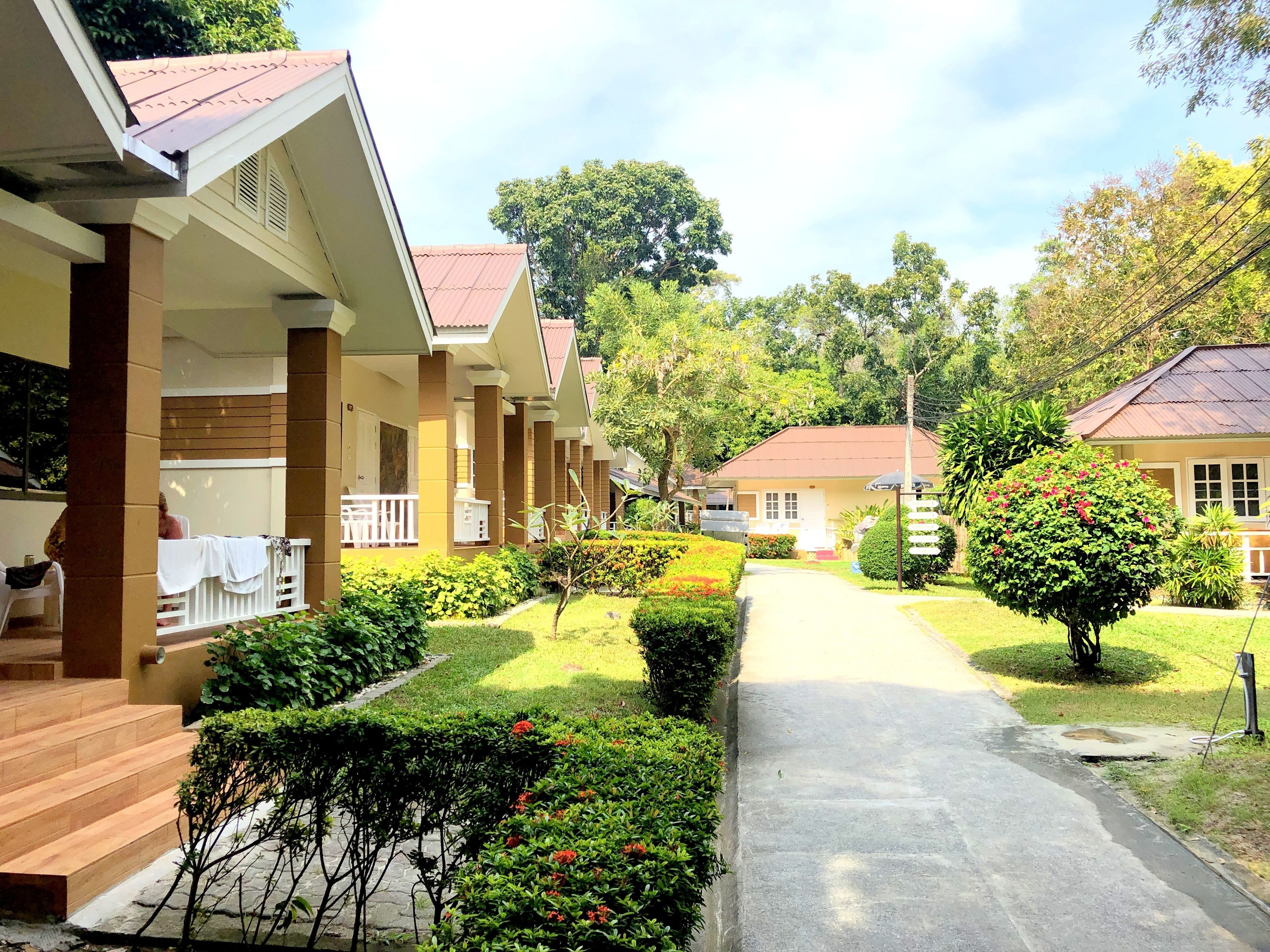 Filas de habitaciones tipo bungaló con un camino central, rodeadas de jardines y árboles bien cuidados.