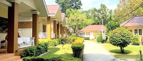 Filas de habitaciones tipo bungaló con un camino central, rodeadas de jardines y árboles bien cuidados.