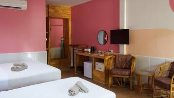A hotel room with two beds, a desk with a computer, a TV, and wicker furniture.