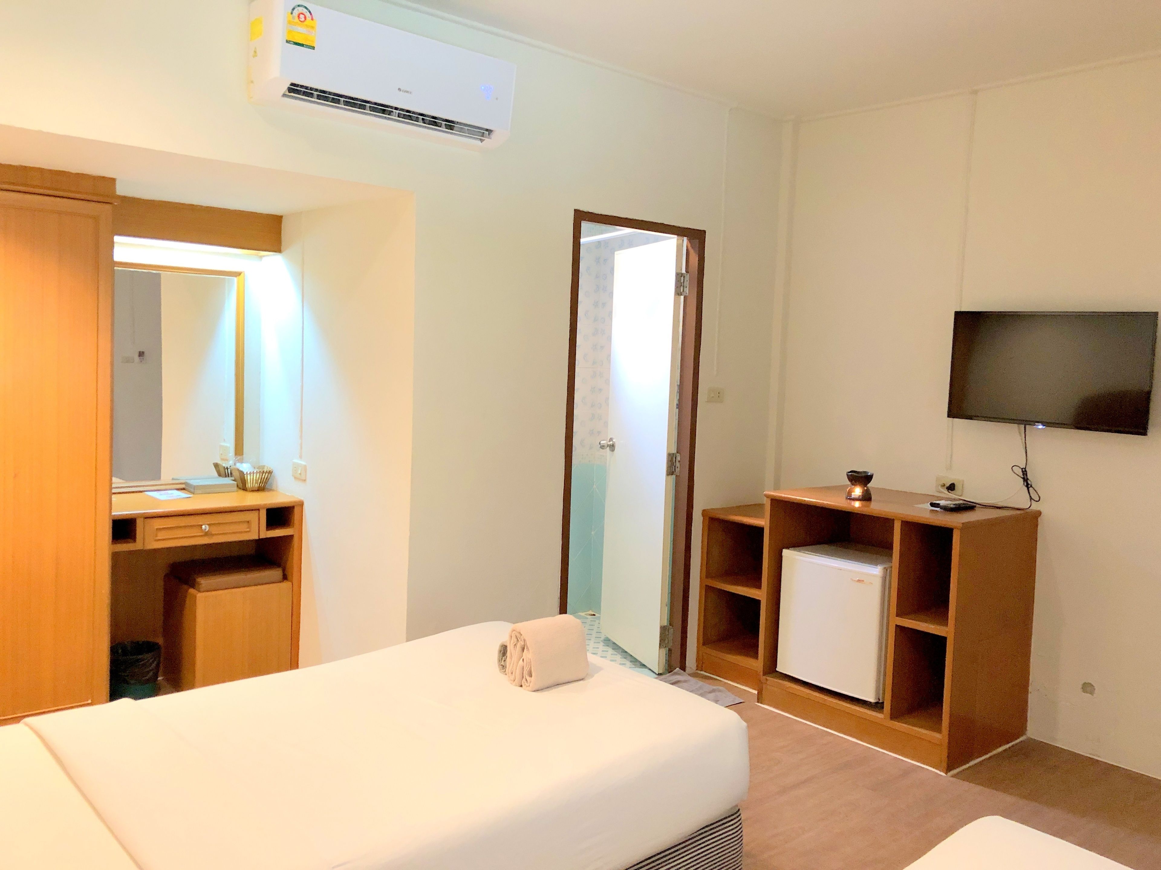 Une chambre d’hôtel comprenant un lit, un bureau avec un miroir, une télévision et un petit réfrigérateur.