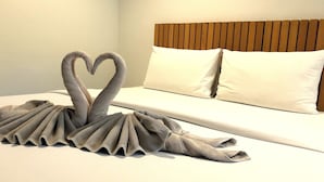 A neatly made bed with a swan towel art in a hotel room. - Malibu Samed resort (Rayong)
