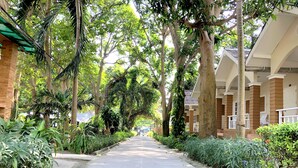 A pathway lined with trees and greenery, leading to a building with a covered walkway and columns. - Malibu Samed resort (Rayong)