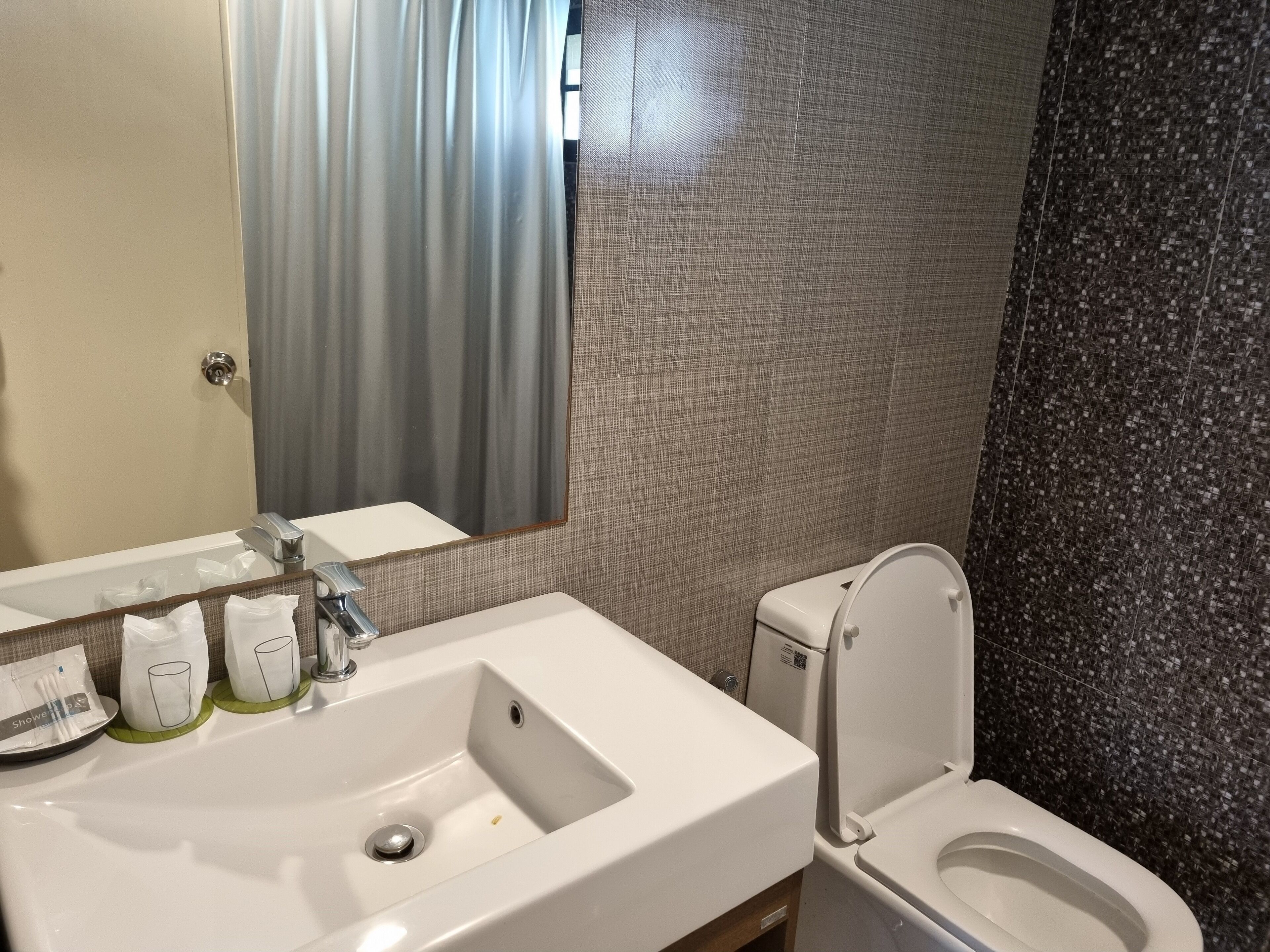 A bathroom with a white sink, a mirror, a toilet, and a shower curtain.