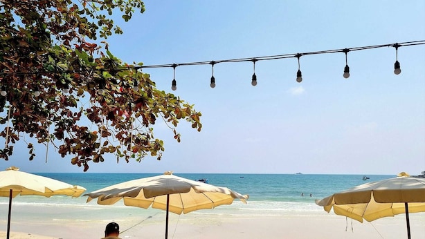 A beachside restaurant with outdoor seating, umbrellas, and a view of the ocean. - Malibu Samed resort (Rayong)