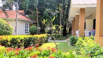 Un jardín con diversas plantas y un edificio con tejado de baldosas.