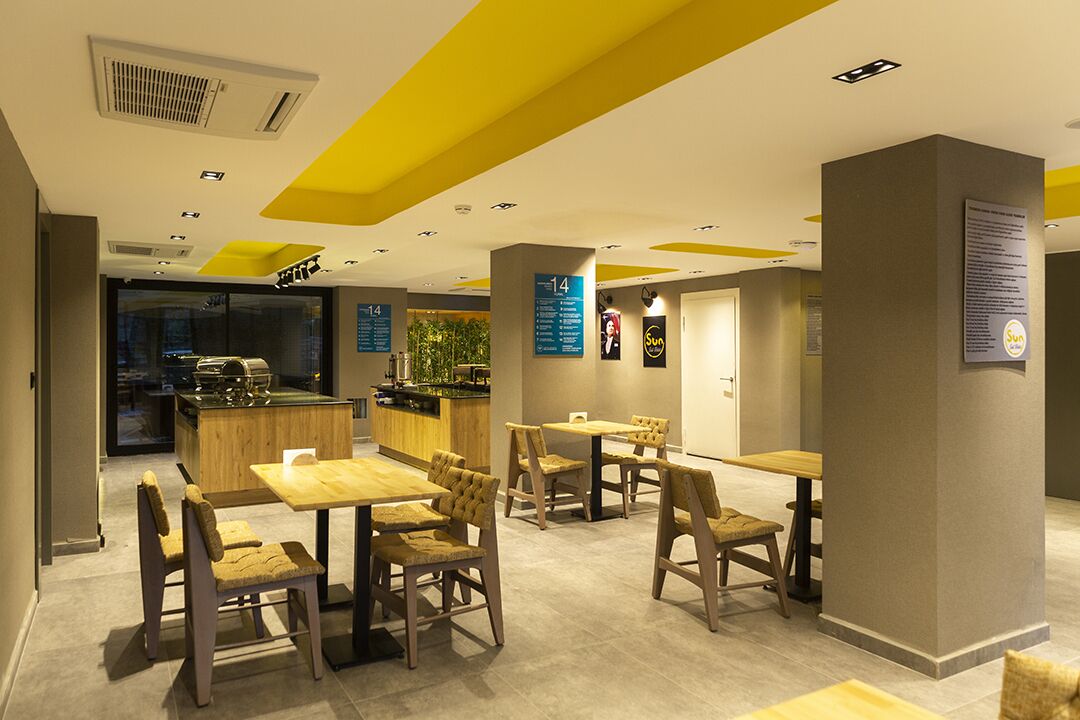 A modern restaurant with wooden furniture and a bright yellow ceiling.