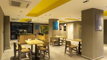 A modern restaurant with wooden furniture and a bright yellow ceiling.