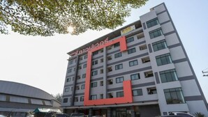 A multi-story hotel with a prominent red and grey facade, featuring a large 'S' logo. - C Tower Hotel (Surat Thani)