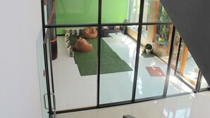 A modern interior with a glass partition, green walls, and a seating area with bean bags and a small table. - C Tower Hotel (Surat Thani)