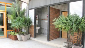 A modern building with a glass entrance, a visible bathroom, and several potted plants. - C Tower Hotel (Surat Thani)