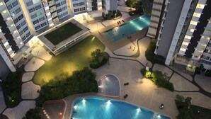 An aerial view of a residential complex with multiple swimming pools, landscaped areas, and high-rise apartment buildings. - City Living with Panoramic Sea Views at Danga Bay (Johor Bahru)