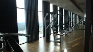 A gym with exercise equipment, large windows, and a view of the city. - City Living with Panoramic Sea Views at Danga Bay (Johor Bahru)