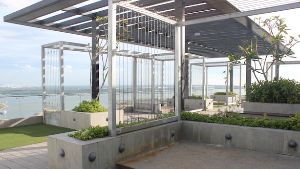 A covered outdoor area with a view of the water, concrete planters with plants, and a metal railing. - City Living with Panoramic Sea Views at Danga Bay (Johor Bahru)