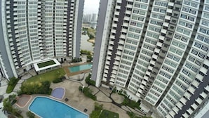 A high-rise residential building with multiple balconies, a swimming pool, and landscaped areas. - City Living with Panoramic Sea Views at Danga Bay (Johor Bahru)