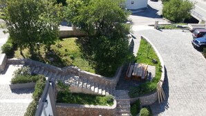 Zona residencial con una escalera de piedra que lleva a una terraza de madera rodeada de vegetación.