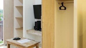 A room with a wooden table, a TV, and a wardrobe. - Green Studio Apartment (Denpasar)