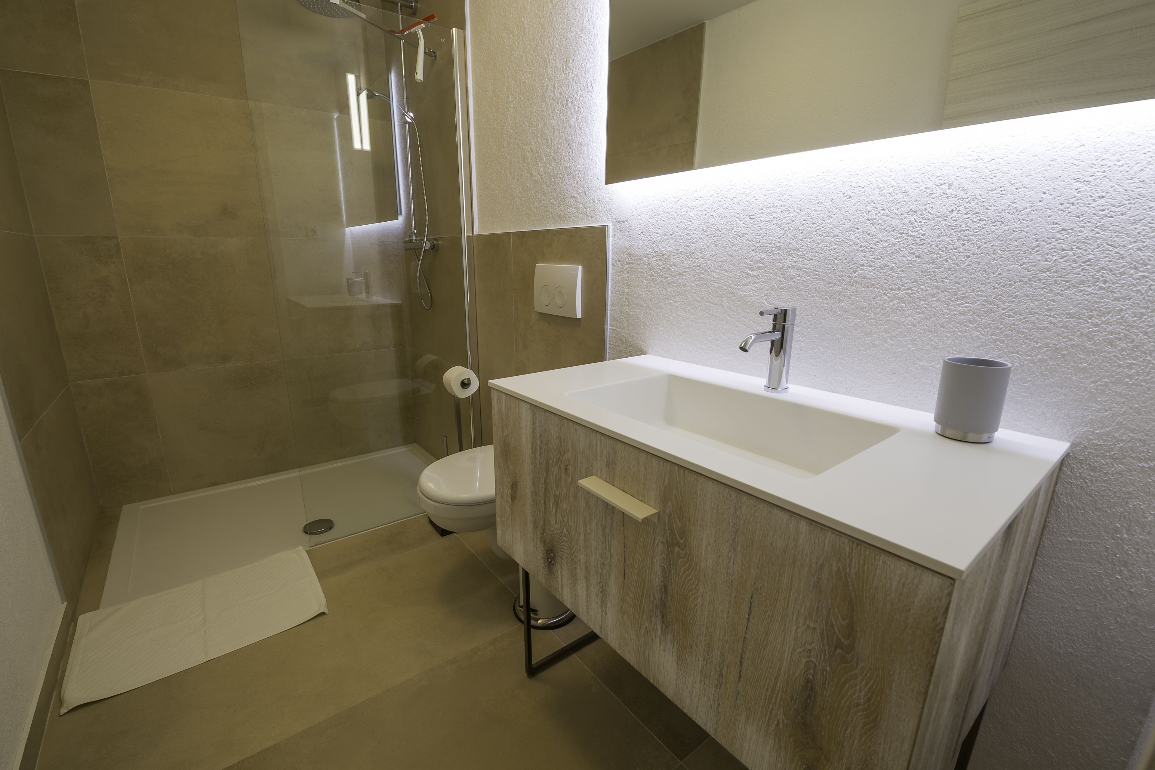 A modern bathroom with a shower, toilet, and sink.