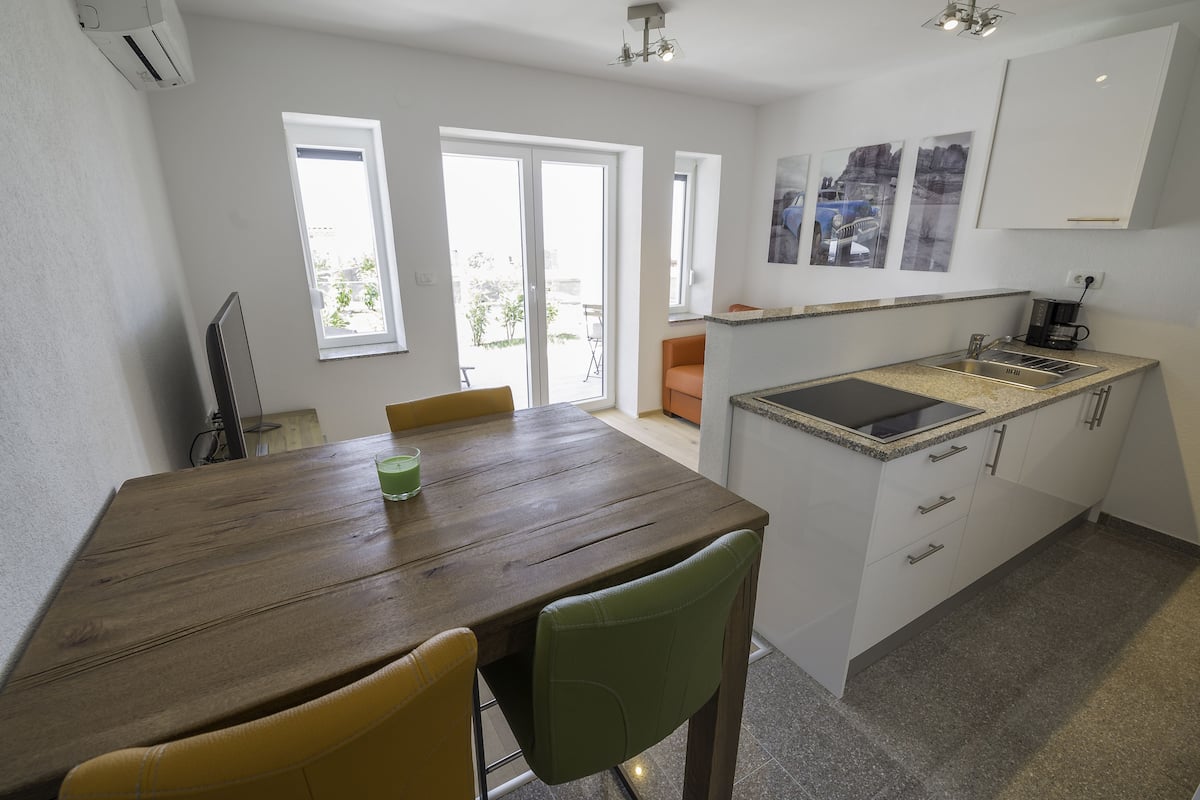 A modern kitchen with a granite countertop, white cabinets, and a built-in stove.