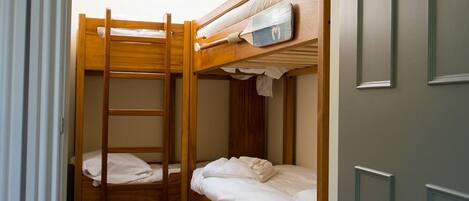 A bunk bed room with a ladder, a small shelf, and a door.