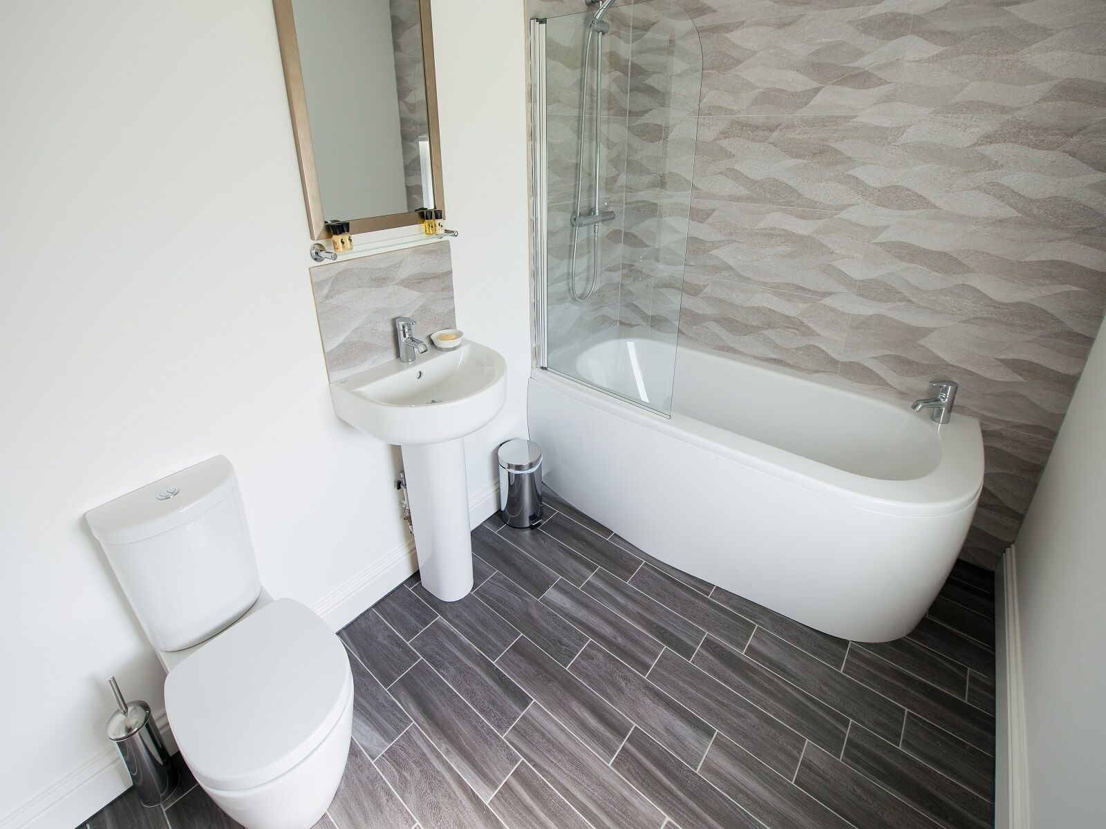 A modern bathroom with a toilet, sink, and bathtub.