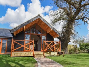 A lodge with a wooden exterior, large windows, and a covered porch. - The Boathouse (Great Yarmouth)