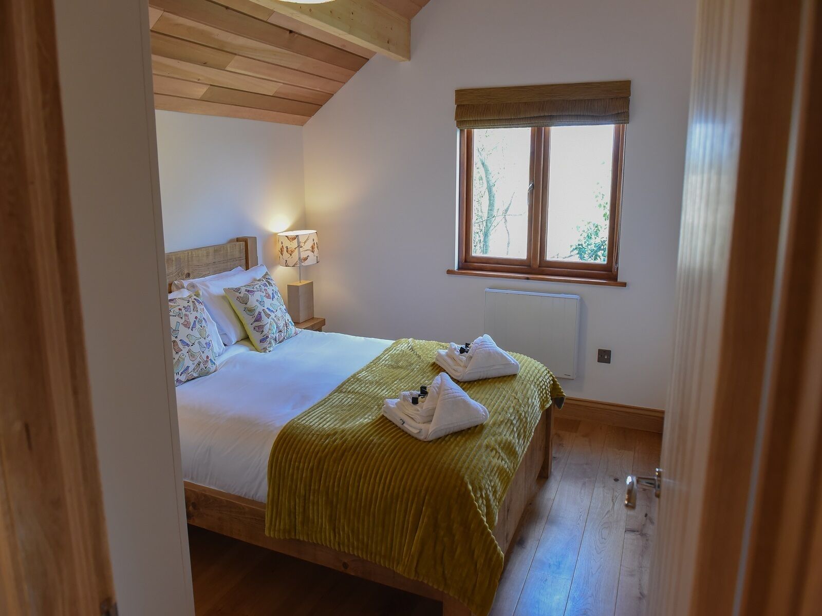 Un dormitorio con cama, lámpara de noche, ventana y radiador.