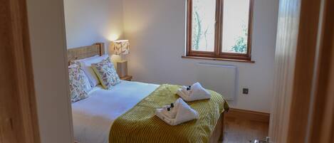 Un dormitorio con cama, lámpara de noche, ventana y radiador.