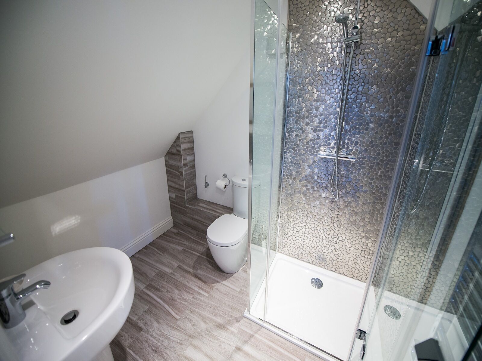 Een moderne badkamer met een douchecabine van glas, een wit toilet en een wastafel.