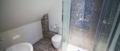 A modern bathroom with a glass shower enclosure, a white toilet, and a sink.
