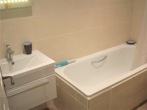 A bathroom with a sink, mirror, and bathtub.