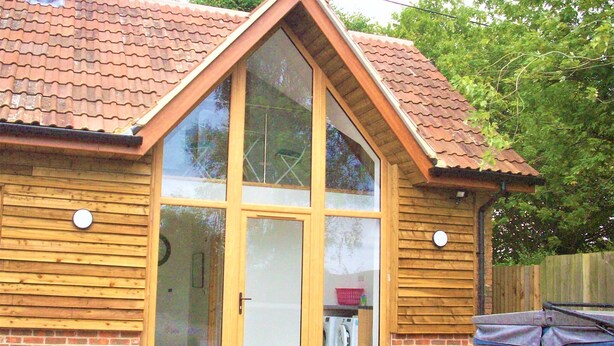Een houten huis met een grote glazen deur en een pannendak.