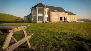 A large house with a spacious lawn, a picnic table, and a clear sky. - Garleton Lodge (Haddington)