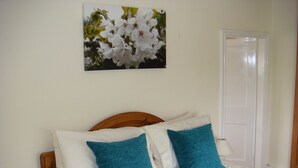 A bedroom with a bed, two pillows, a nightstand, a lamp, and a door. - Elm Tree Farm Bed & Breakfast (Withernsea)