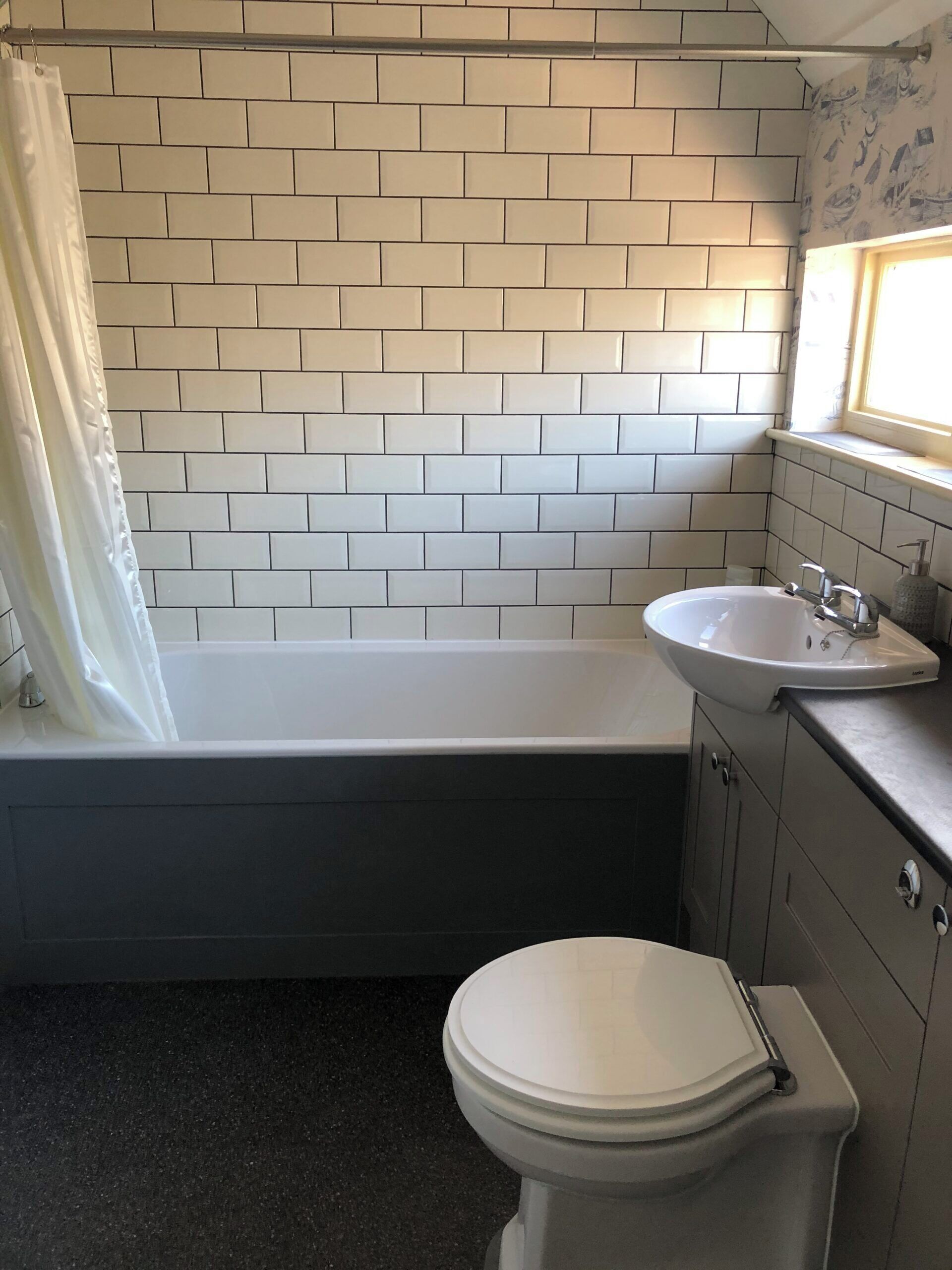 Een badkamer met een witte badkuip, een wit wastafelmeubel en een toilet.