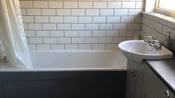 Een badkamer met een witte badkuip, een wit wastafelmeubel en een toilet.
