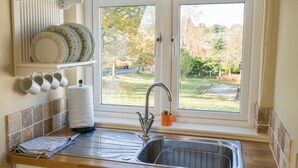 A kitchen with a window, a sink, and a dish rack. - Dunroamin Apartment (Glasgow)