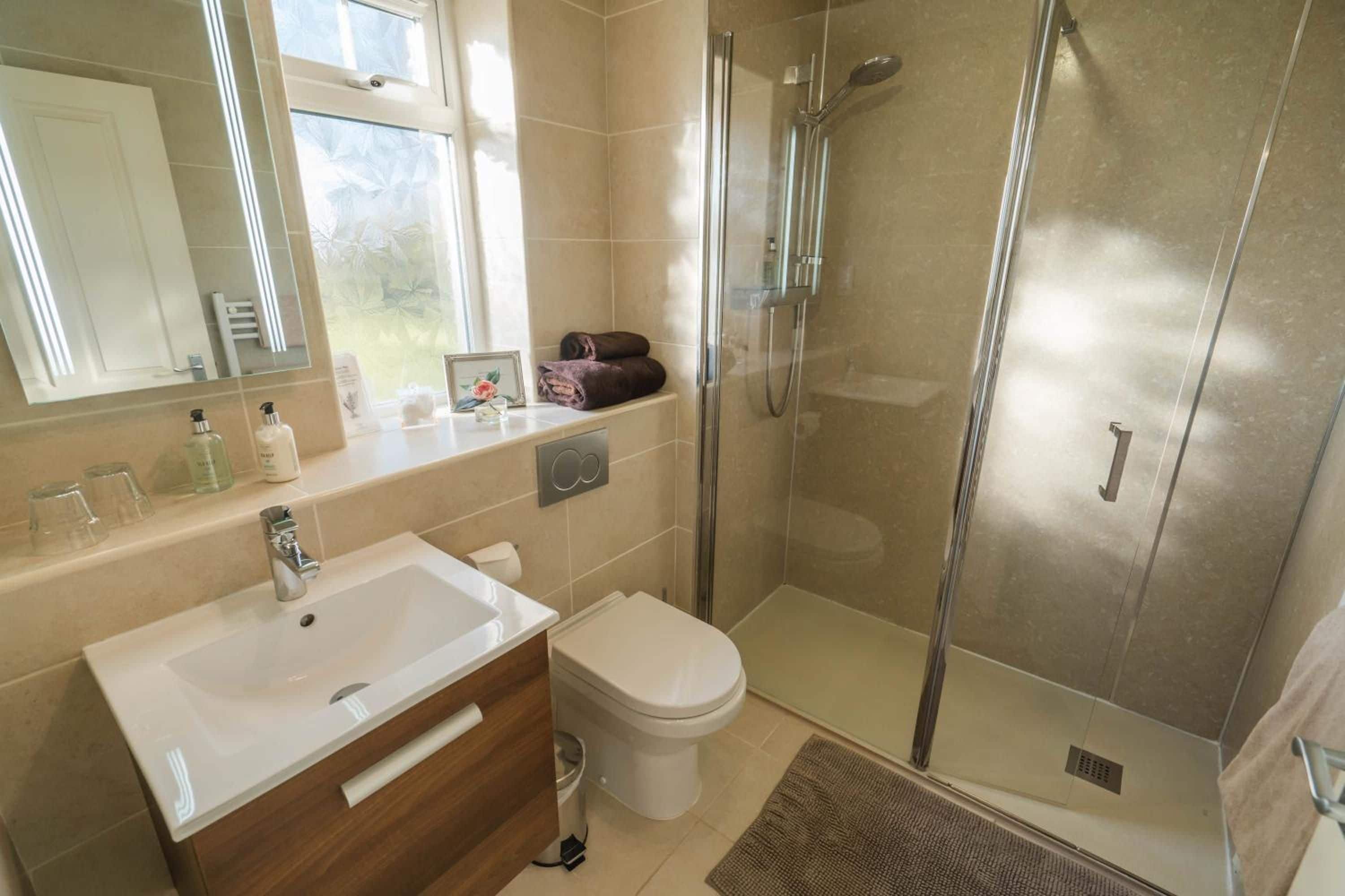 Un baño moderno con ducha envuelta en vidrio, un lavabo blanco y un inodoro.