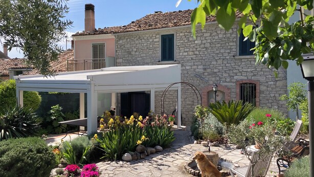 A stone house with a garden patio, outdoor seating, and a dog. - Art & Breakfast (Ripabottoni)