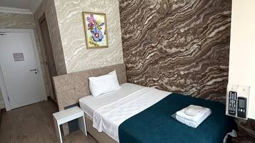Una camera d'albergo con un letto, un comodino e un quadro appeso al muro.