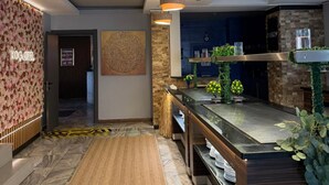 A modern hotel lobby with a reception desk, a decorative wall, a wooden bench, and a bar area. - Koc Hotel (Karasu)