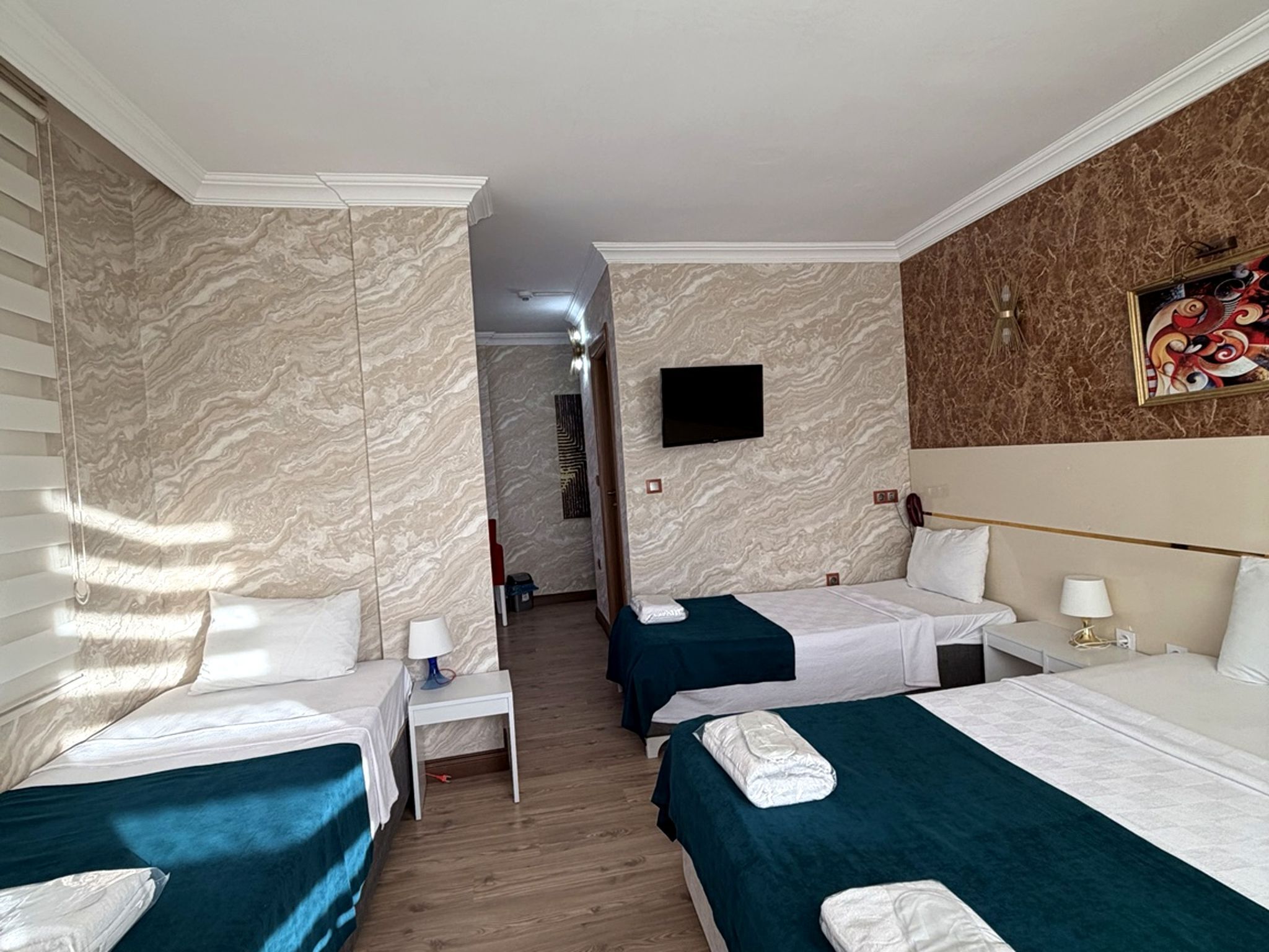 Habitación de hotel con dos camas, un televisor y un cuadro en la pared.