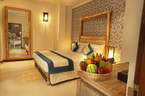 Relax in a spacious room with a large bed, a wicker basket of fresh fruits, and a large mirror.