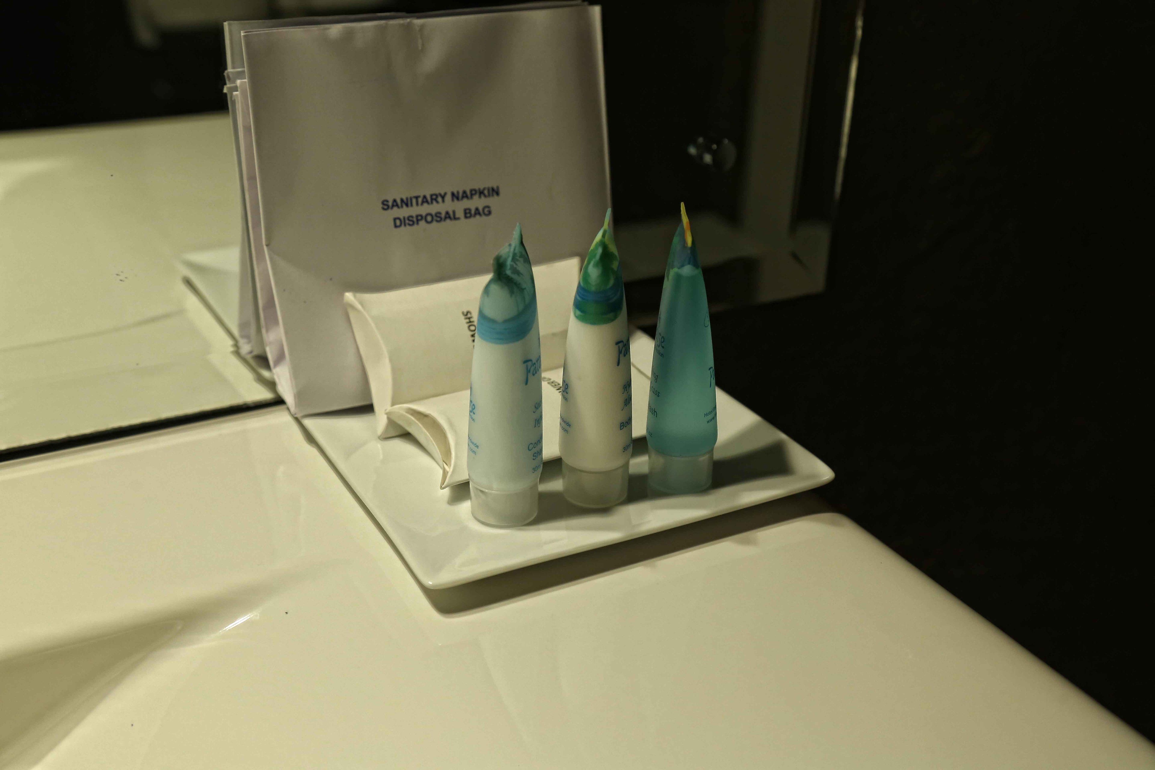 A sanitary napkin disposal bag and three bottles on a white surface.