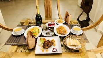 A dining table set with various dishes, including a bottle of champagne, plates of food, and a basket of bread.