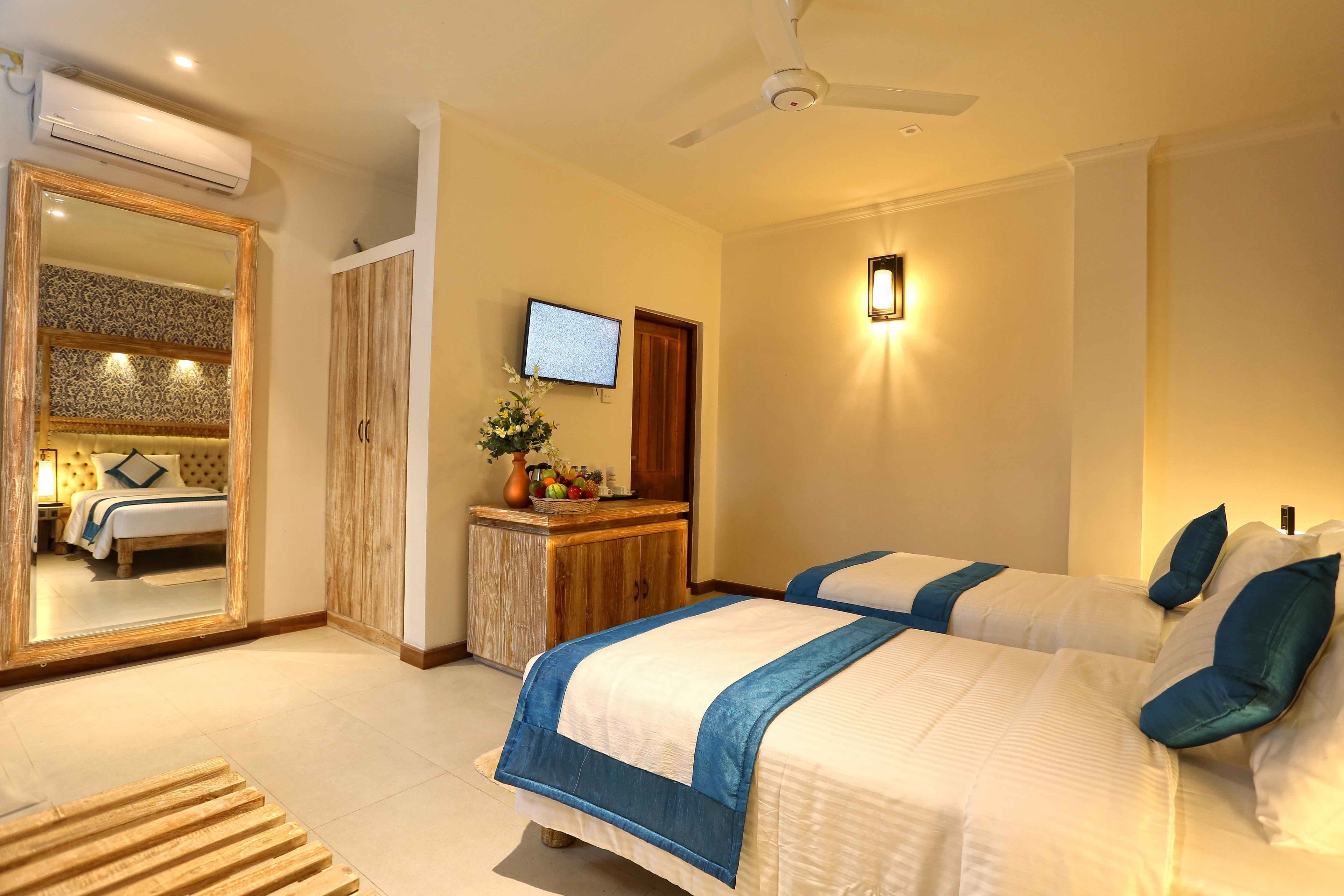 A hotel room with two beds, a wooden desk, a TV, and a mirror.