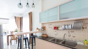 A modern kitchen with a central island, bar stools, a double sink, and a backsplash with food-themed tiles.
